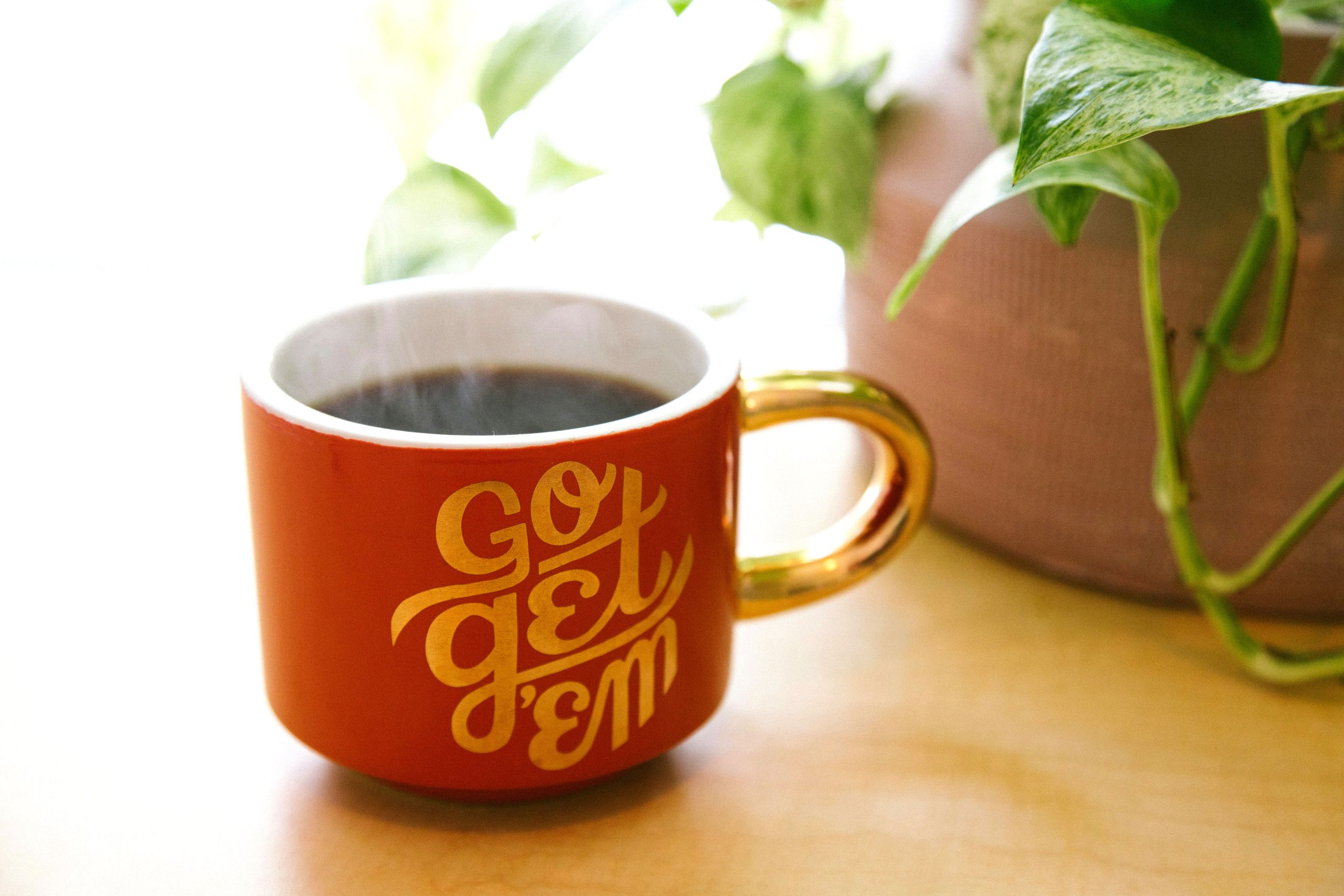Tasse mit motivierendem Spruch 'go get ´em' auf Schreibtisch, ermutigt zu Initiative und Aktion in New Leadership und digitaler Transformation.