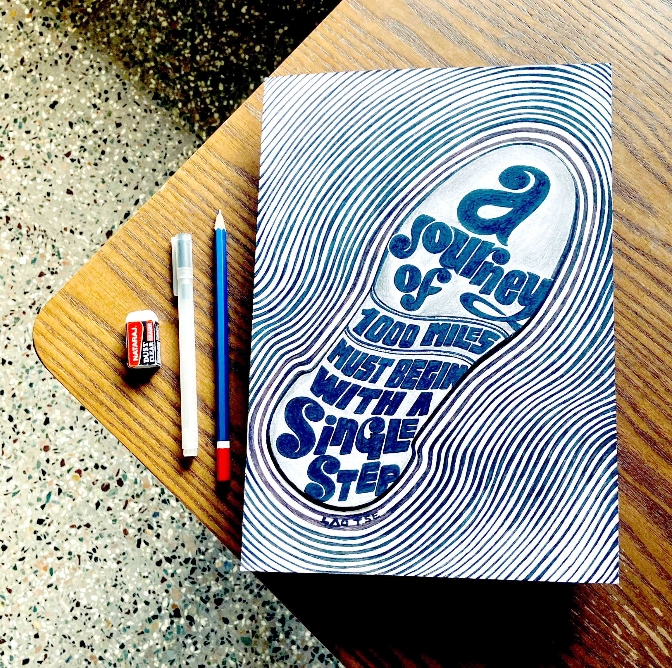Zeichnung eines Schuhsohlenabdrucks mit dem Spruch 'a journey of 1000 miles must begin with a single step' auf einem Schreibtisch, inspiriert zu ersten Schritten in der persönlichen Entwicklung und Transformation.